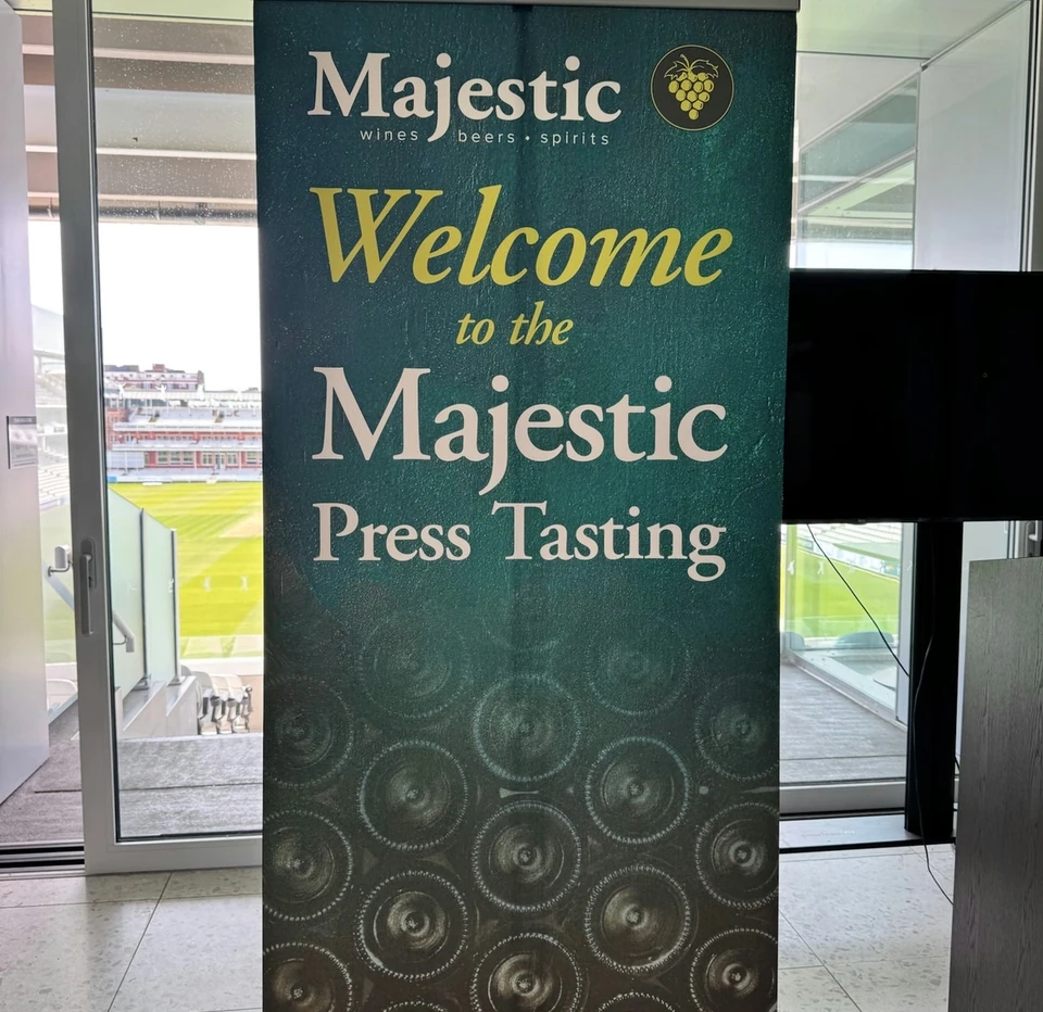 Majestic Press Tasting welcome banner beside windows overlooking a sports ground