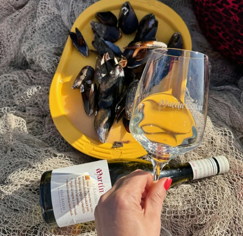 A glass of Albariño and mussels on a yellow plate beside a wine bottle