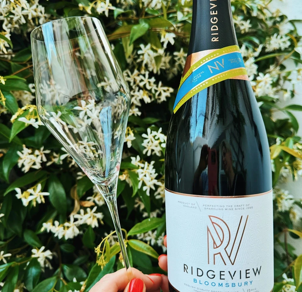 Ridgeview Bloomsbury sparkling wine bottle and flute held against flowering greenery
