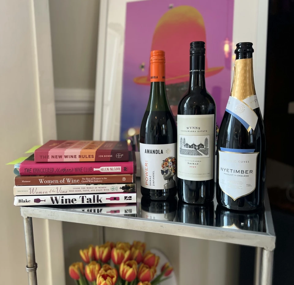 Books about women in wine and three wine bottles on a mirrored drinks trolley