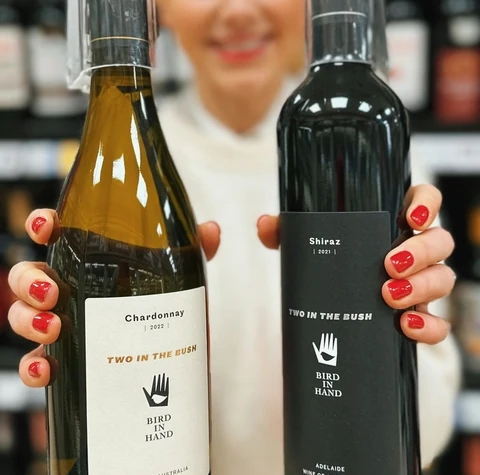 Person holding Two in the Bush Chardonnay and Shiraz wine bottles