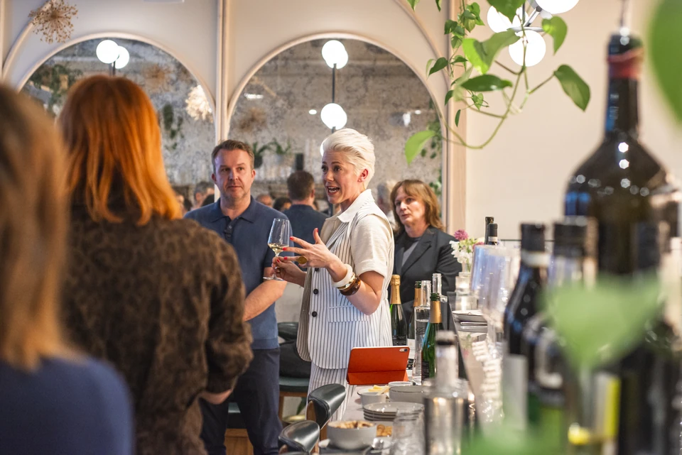 Wine host speaking to guests at a tasting bar at Stem + Stem