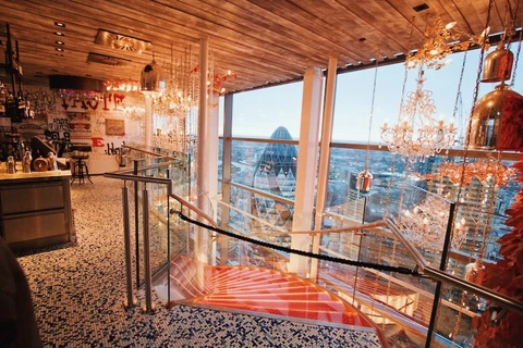 Interior of Duck & Waffle restaurant with chandeliers, staircase and London skyline views.