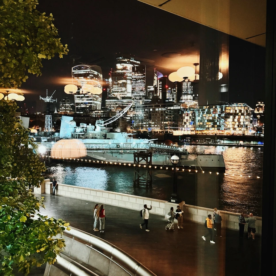 Night-time view of the River Thames, a moored ship and illuminated London skyline