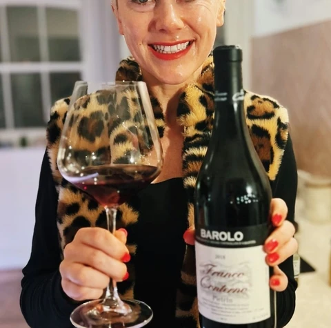 Woman holding a glass of red wine and a bottle of Barolo