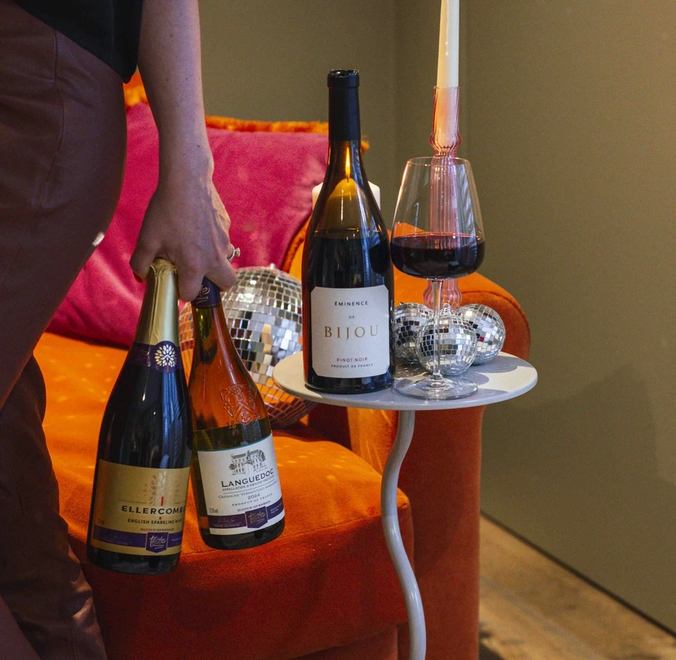 Sainsbury's wine bottles and glasses beside a lit candle in a colourful lounge setting