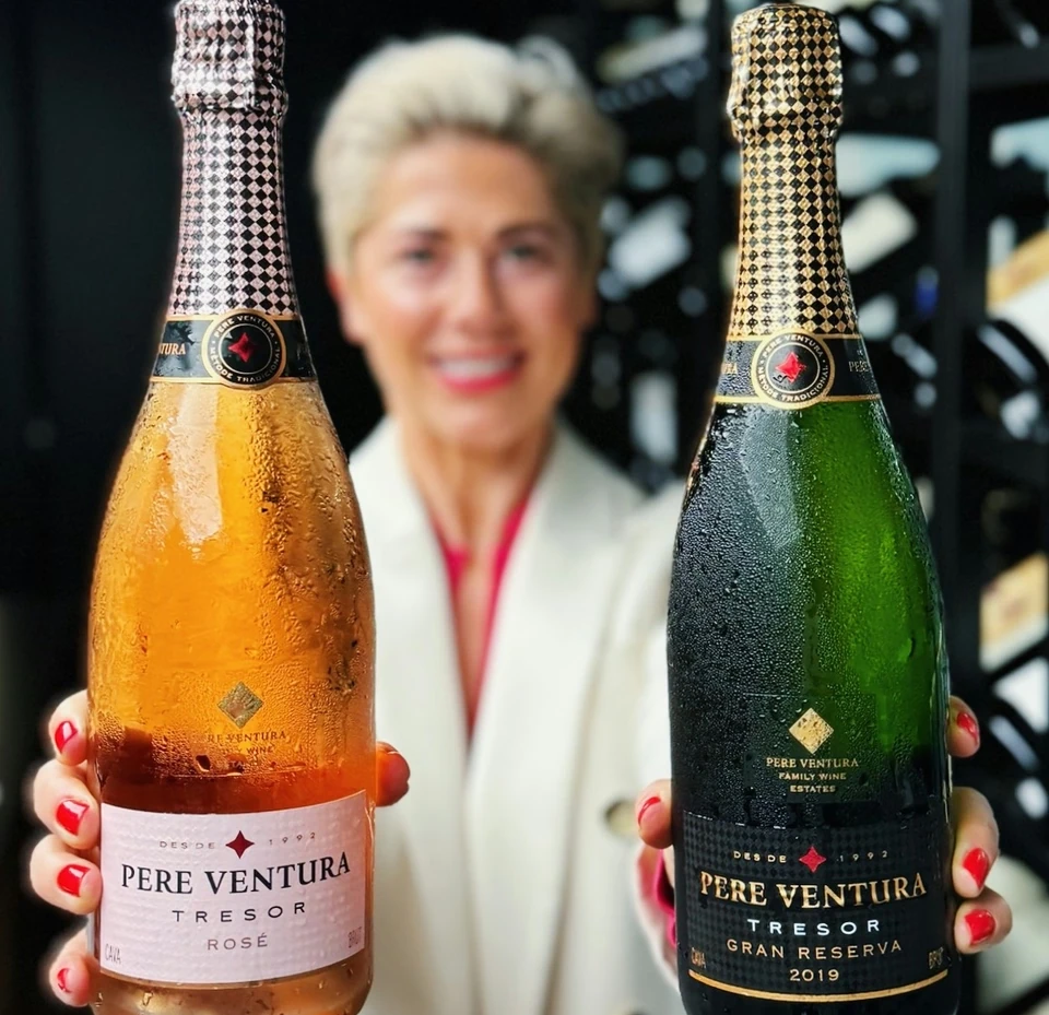 Two chilled Pere Ventura Cava bottles held in front of a blurred person