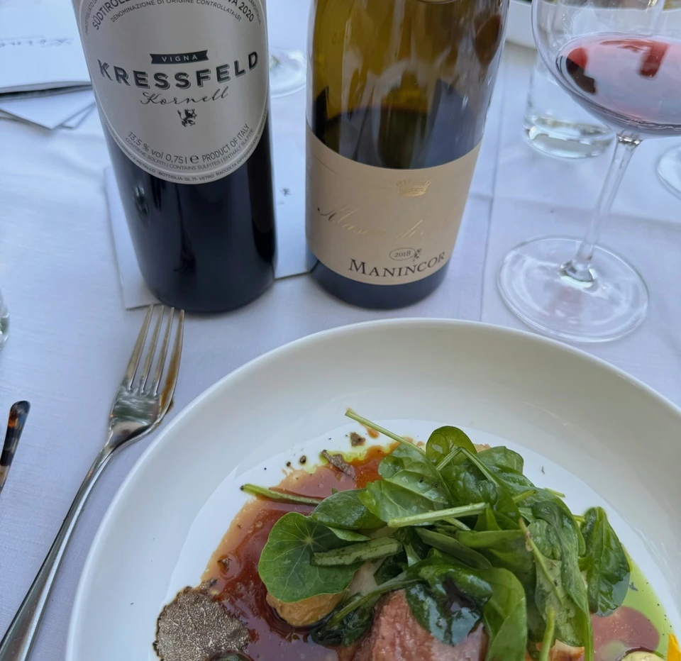A bottle of Kressfeld Merlot Riserva and another wine beside a plated dish