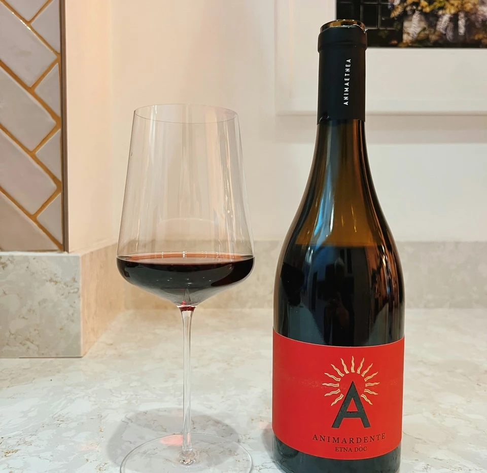 Bottle of Animardente Etna DOC red wine beside a glass of red wine