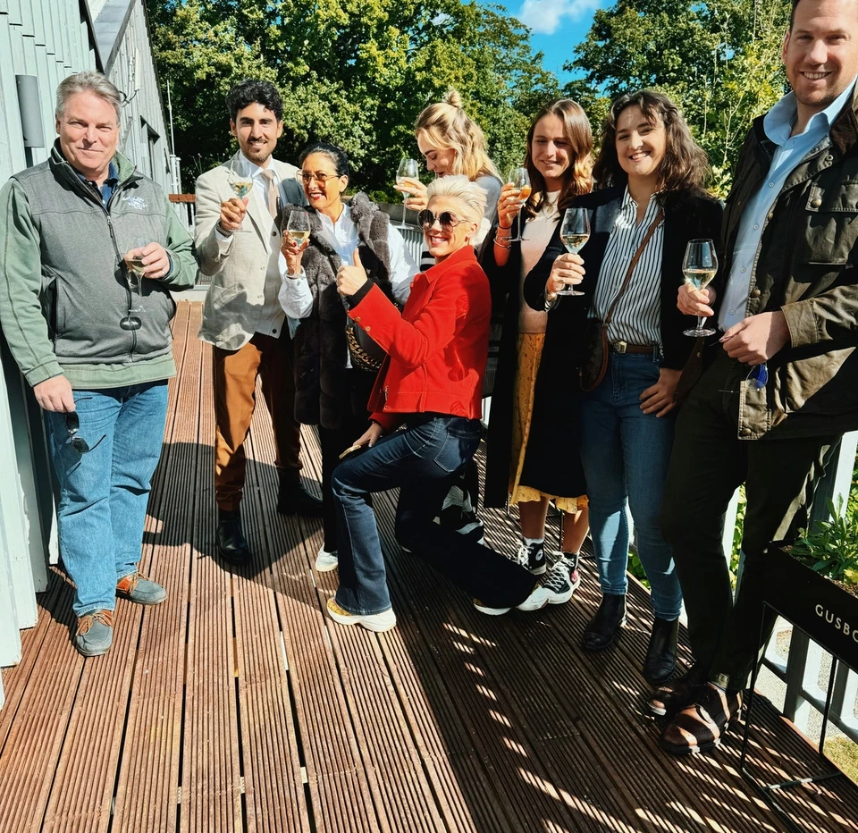 A group of people holding wine glasses on a sunny Gusbourne winery terrace