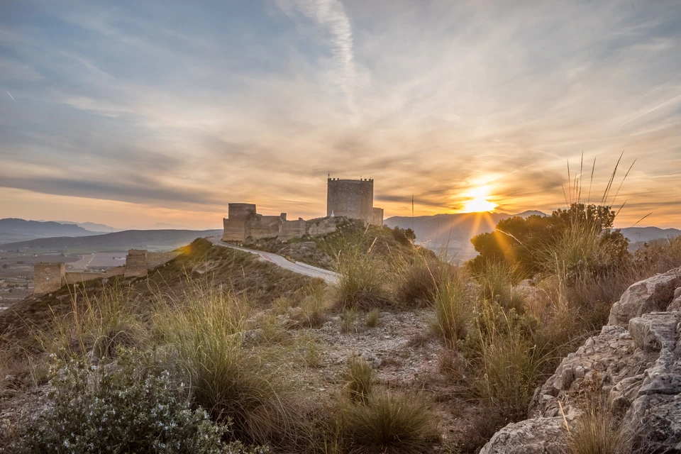 Castillo de Jumilla at sunset above the surrounding hills