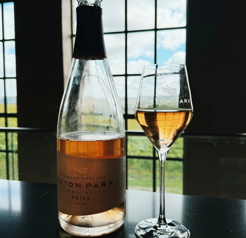 Exton Park rosé bottle and filled wine glass by a window