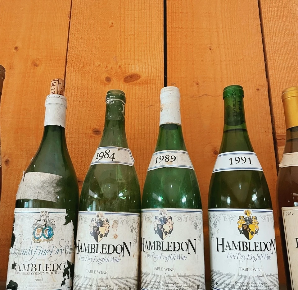 Vintage Hambledon English wine bottles labelled 1984, 1989 and 1991 on a wooden shelf