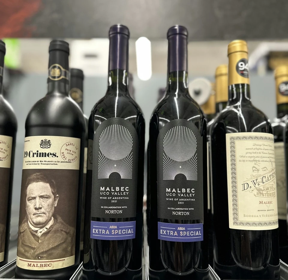 Malbec bottles displayed on a wine shelf, including Norton Uco Valley and 19 Crimes labels