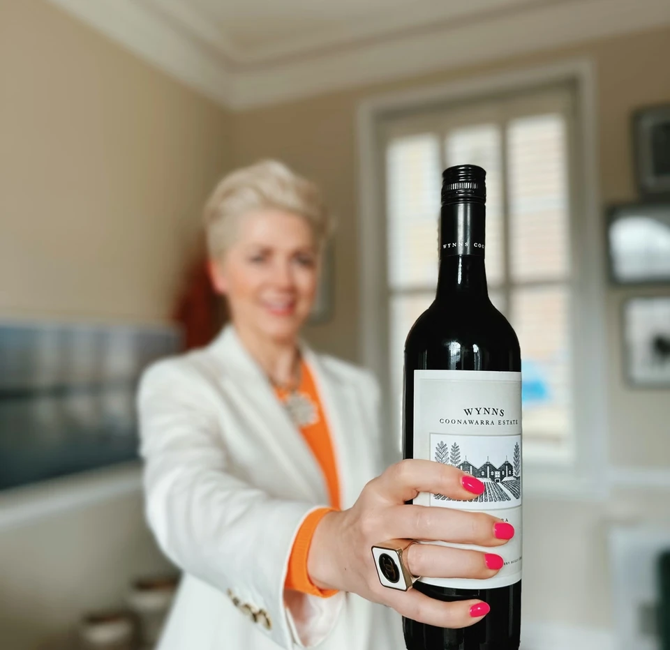 Person holding a bottle of Wynns Coonawarra Estate wine indoors