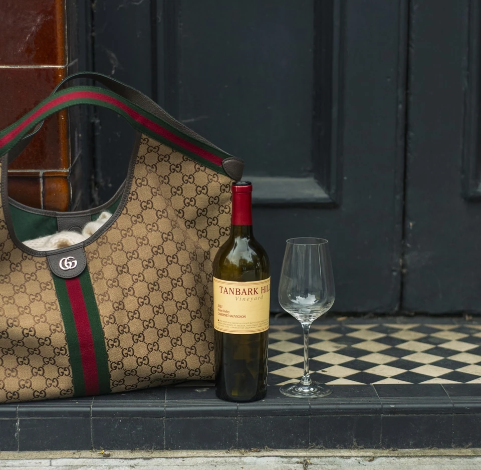 Tanbark Hill Cabernet Sauvignon beside a wine glass and Gucci bag on a tiled doorstep