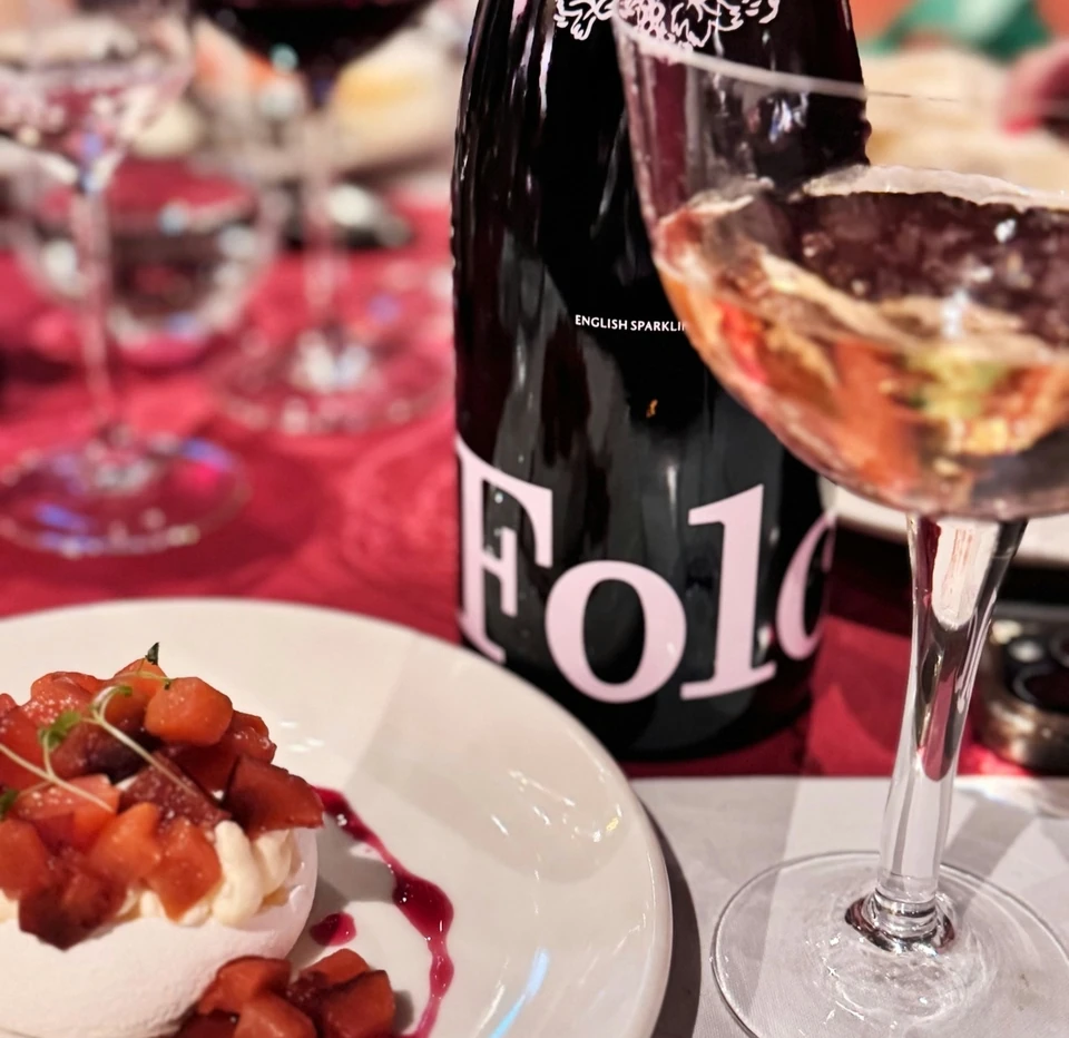 Folc English sparkling wine bottle, filled wine glass and plated dessert at a tasting table