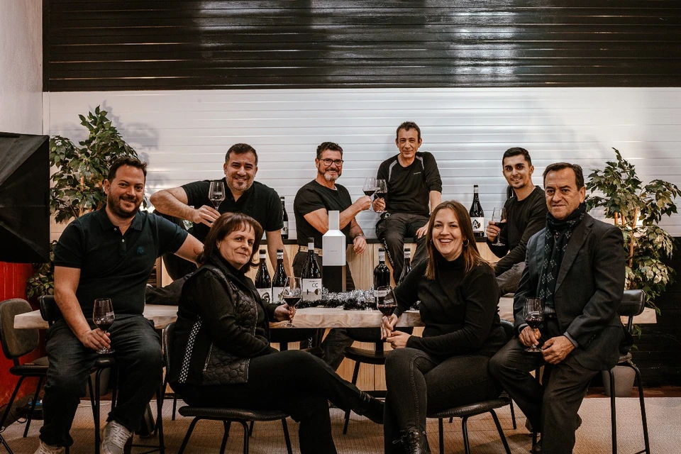 Team building group posing with wine glasses and bottles in a winery tasting room