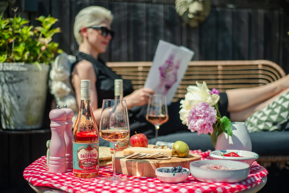 Outdoor Rhône wine tasting with Les Dauphins rosé, glasses, flowers, fruit and cheese