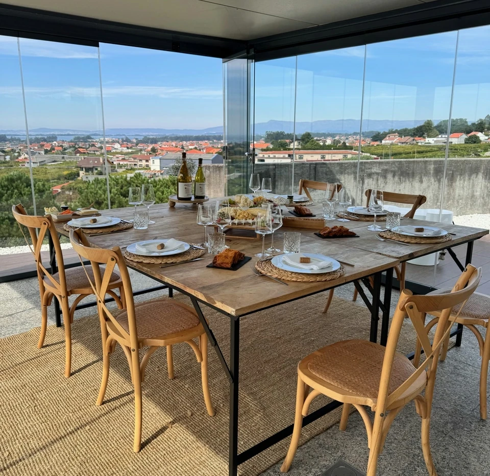 Rías Baixas wine tasting table with glasses, bottles and food overlooking a coastal town and hills