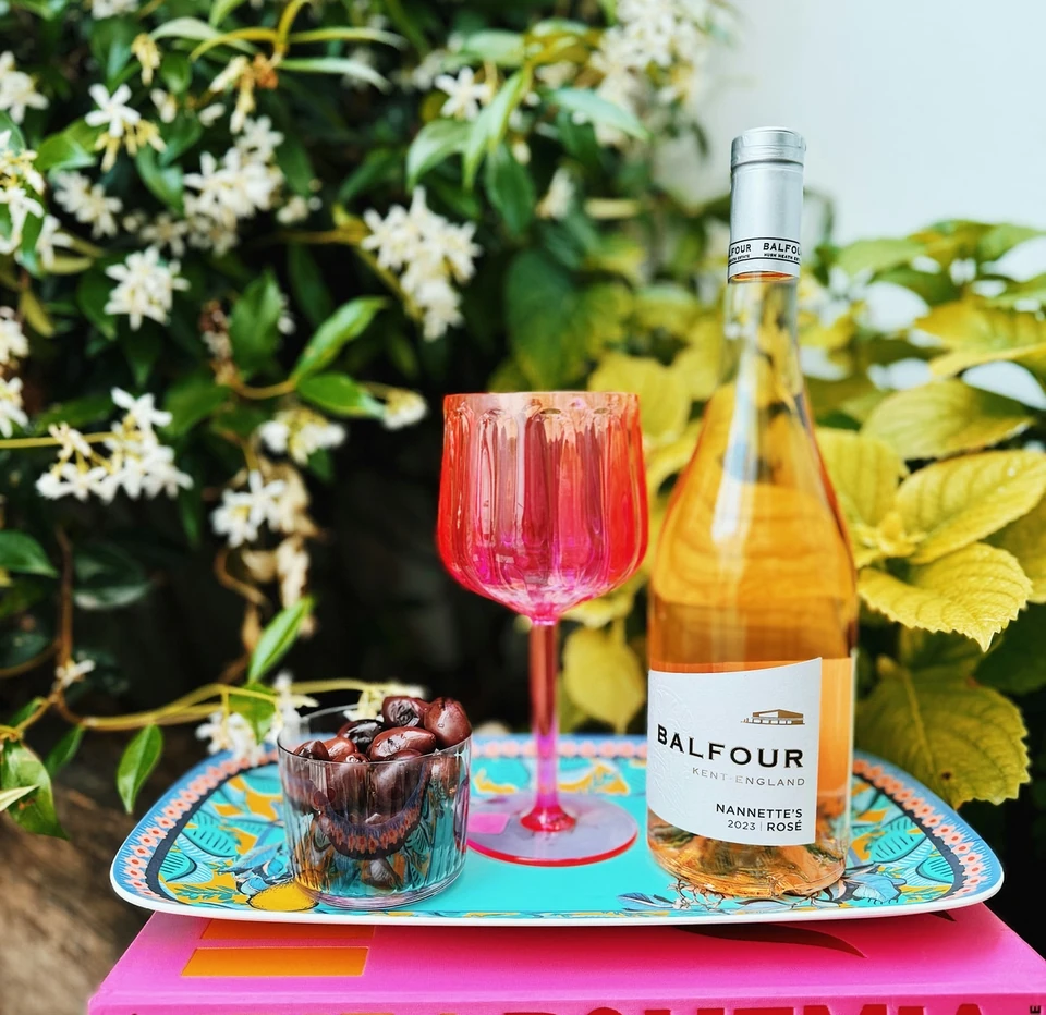 Balfour Nannette's Rosé beside a pink wine glass and cherries on a colourful tray