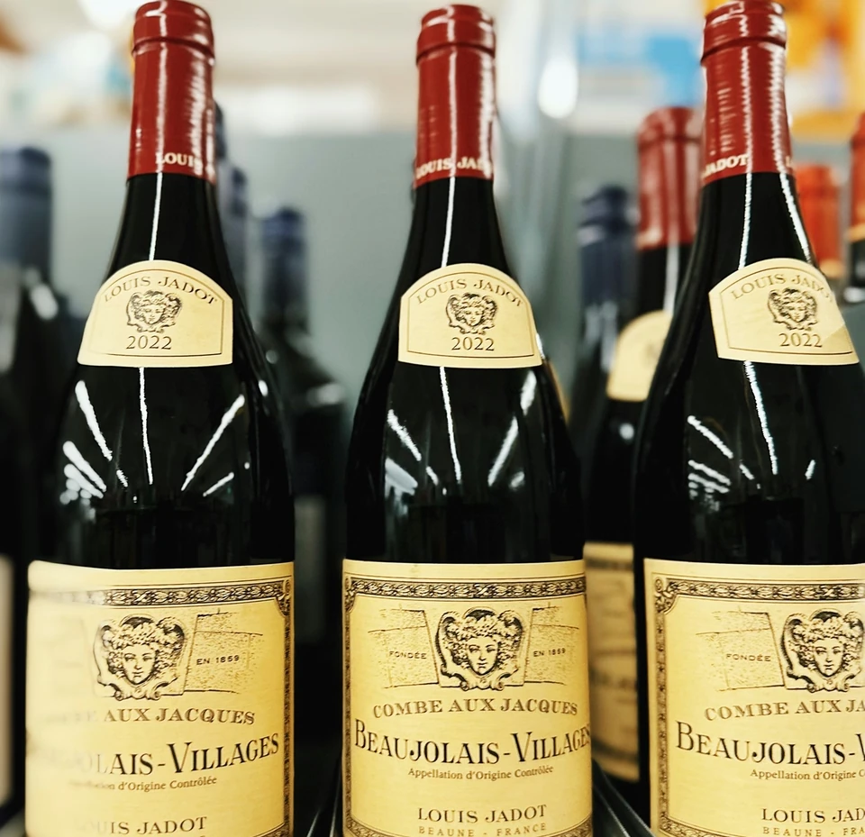 Three Louis Jadot Beaujolais-Villages bottles on a display shelf