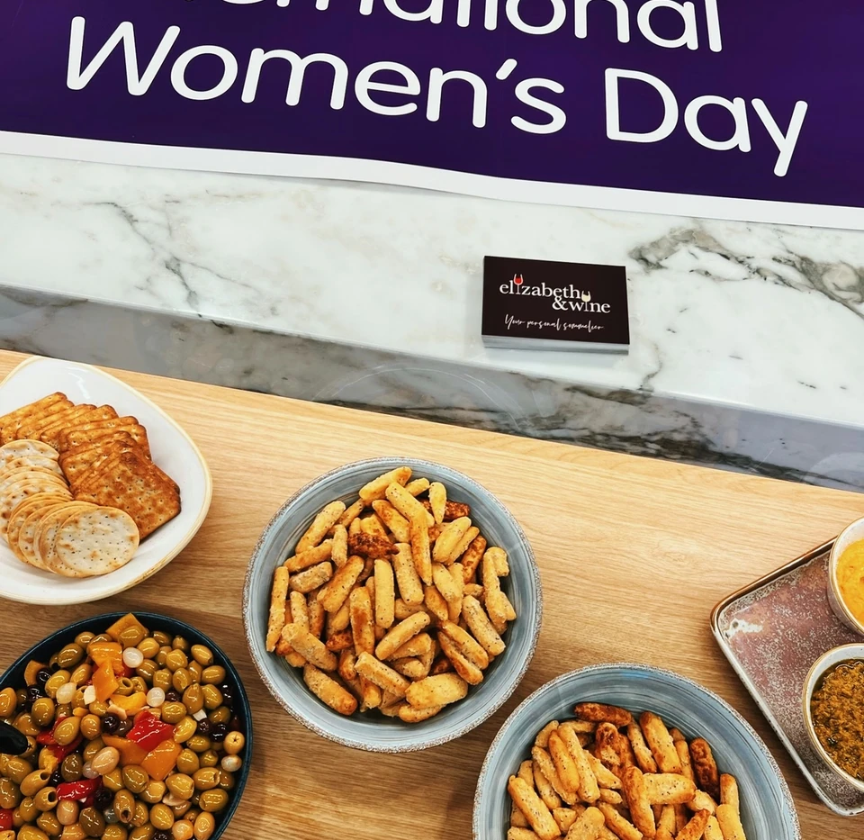 International Women's Day sign above bowls of crackers, olives and dips