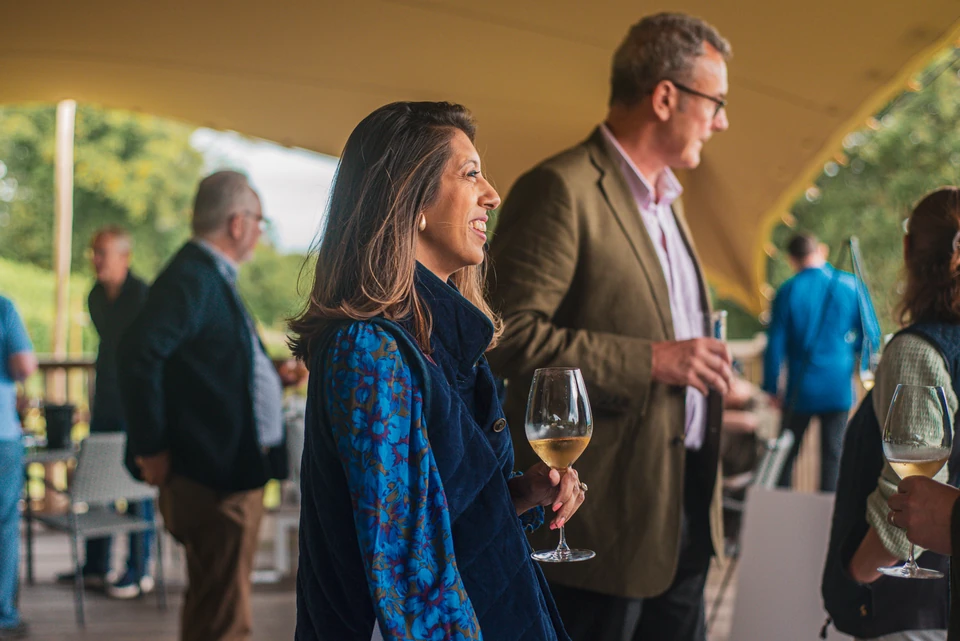 Guests mingle under a covered terrace, holding glasses of white wine