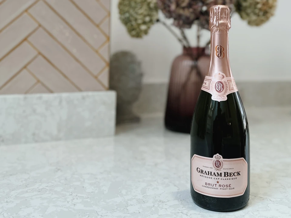 Bottle of Graham Beck Brut Rosé Cap Classique on a pale marble surface