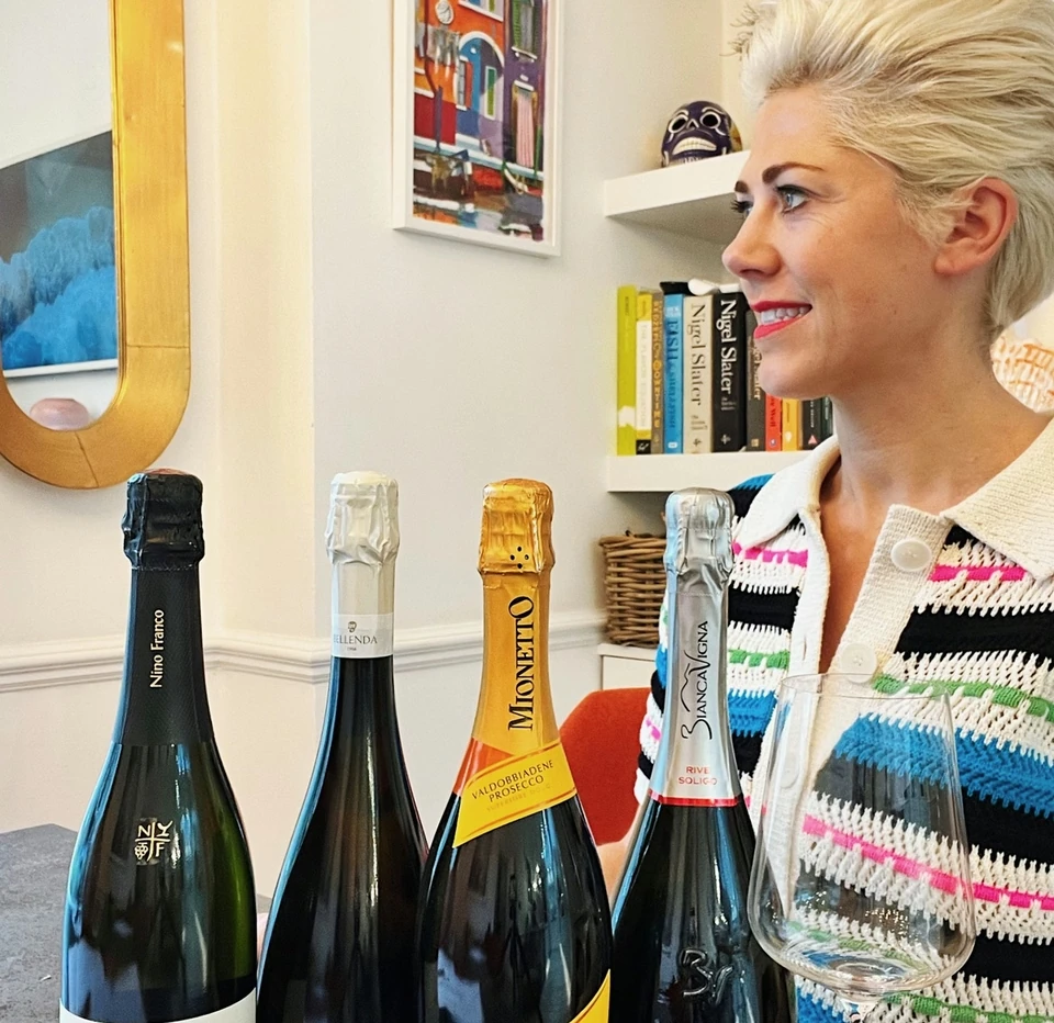 Woman beside four Prosecco bottles and a wine glass