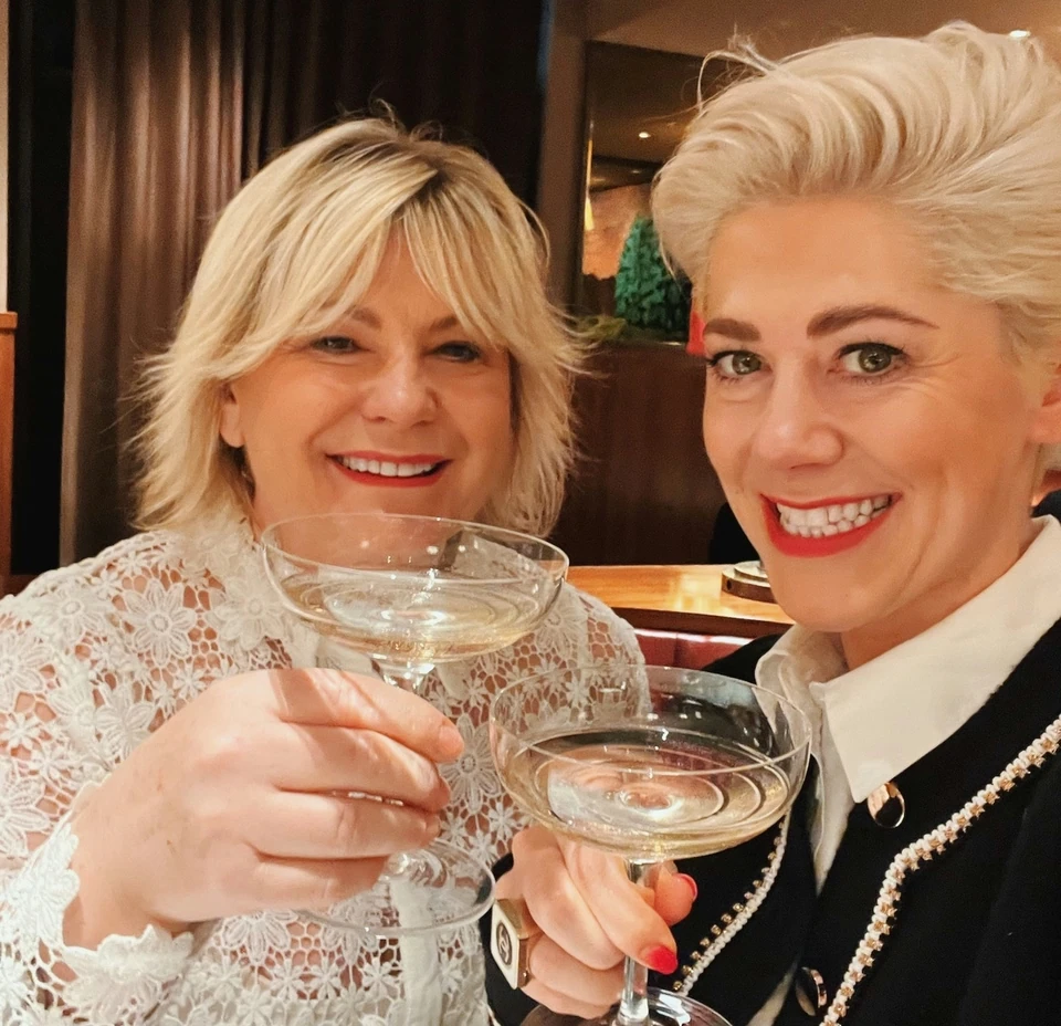 Two women raising coupe glasses in The Colony Grill Room