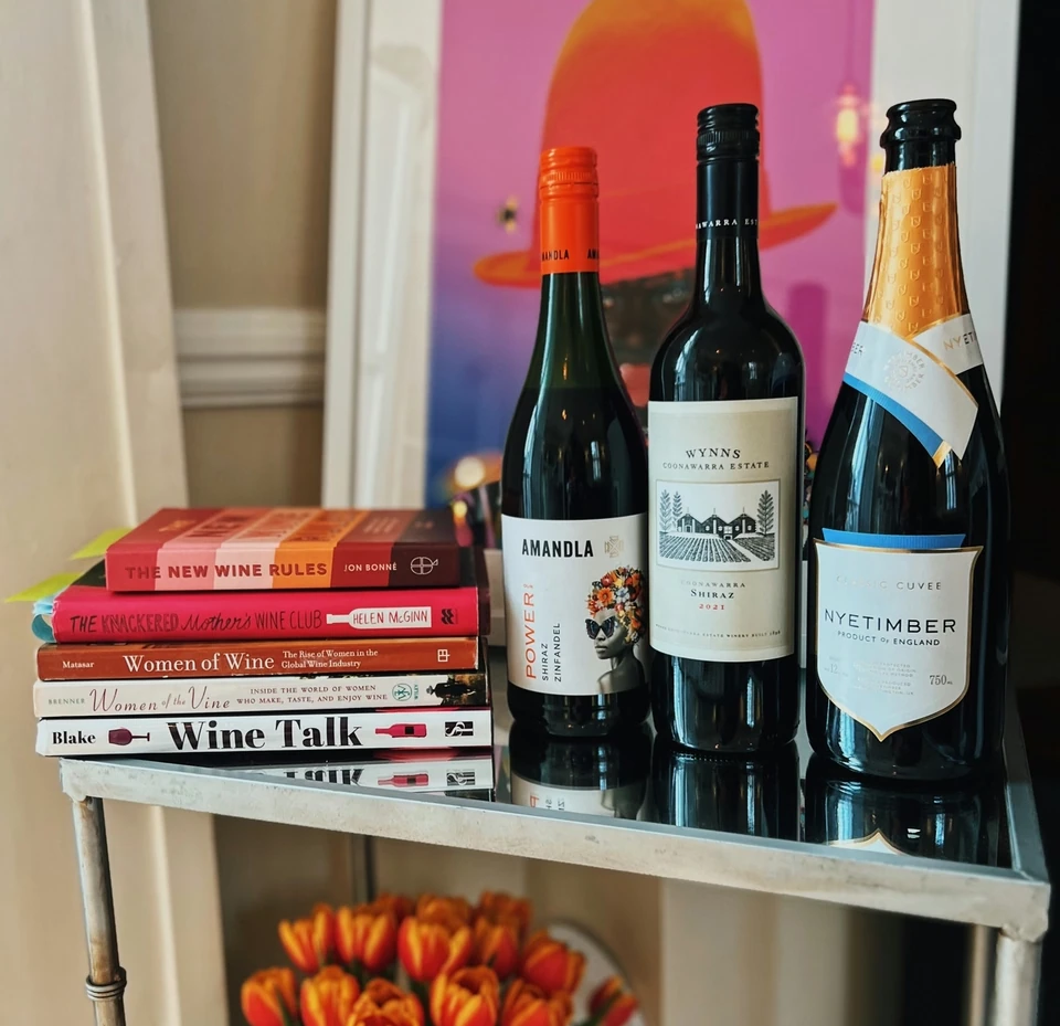 Nyetimber bottle with two other wines and books about women in wine beside orange tulips