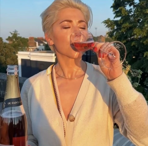 A person drinks rosé Champagne outdoors beside a bottle of De Saint-Gall