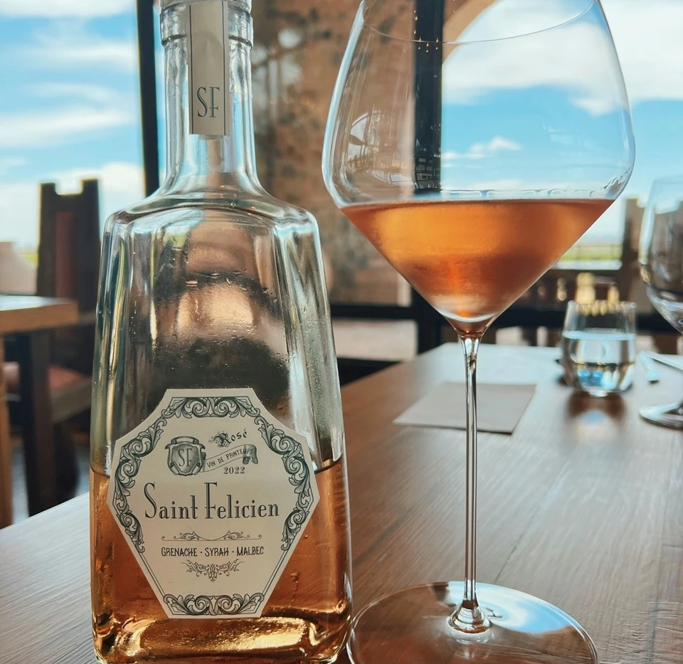Bottle of Saint Felicien rosé and a glass of rosé wine on a wooden table