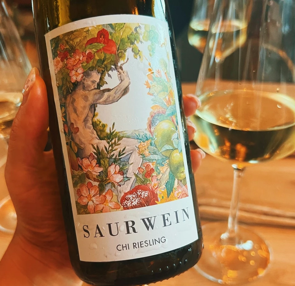 A Saurwein Chi Riesling bottle held above wine glasses at a tasting