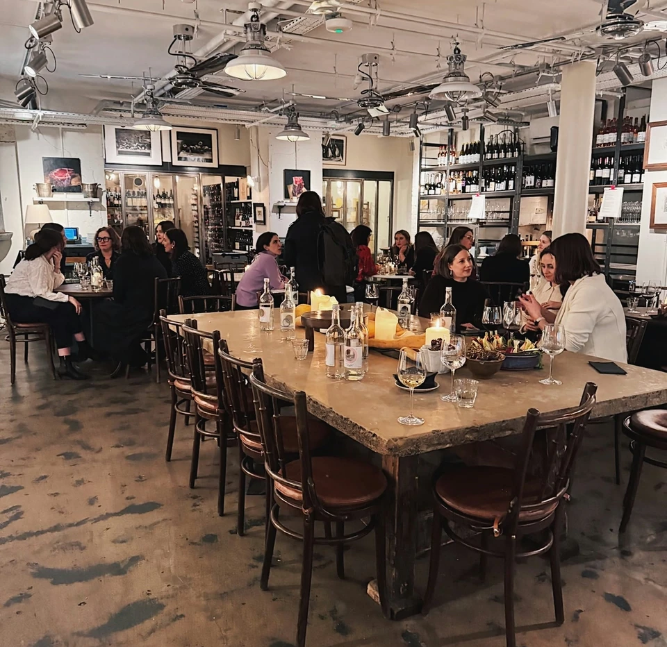 Guests enjoy wine and food at tables in a lively indoor tasting venue