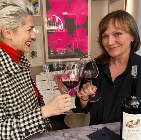Two women clinking glasses beside a Fontodi Chianti Classico bottle