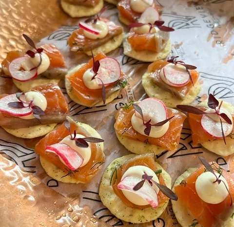 Canapés topped with smoked salmon, radish, cream and microgreens on Ridgeview-branded paper