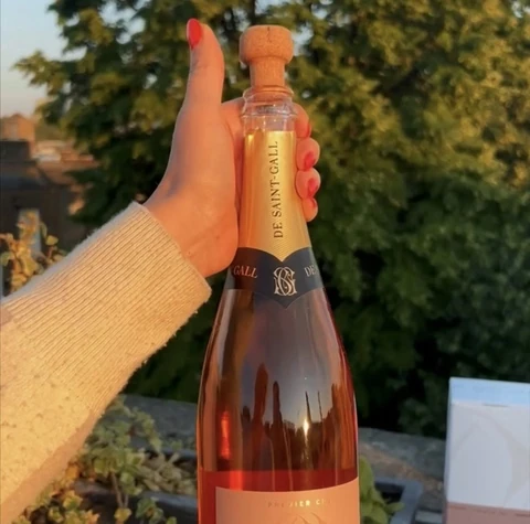 Hand holding a bottle of De Saint Gall rosé Champagne outdoors