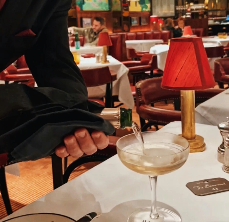 Sparkling wine being poured into a coupe at The Colony Grill Room