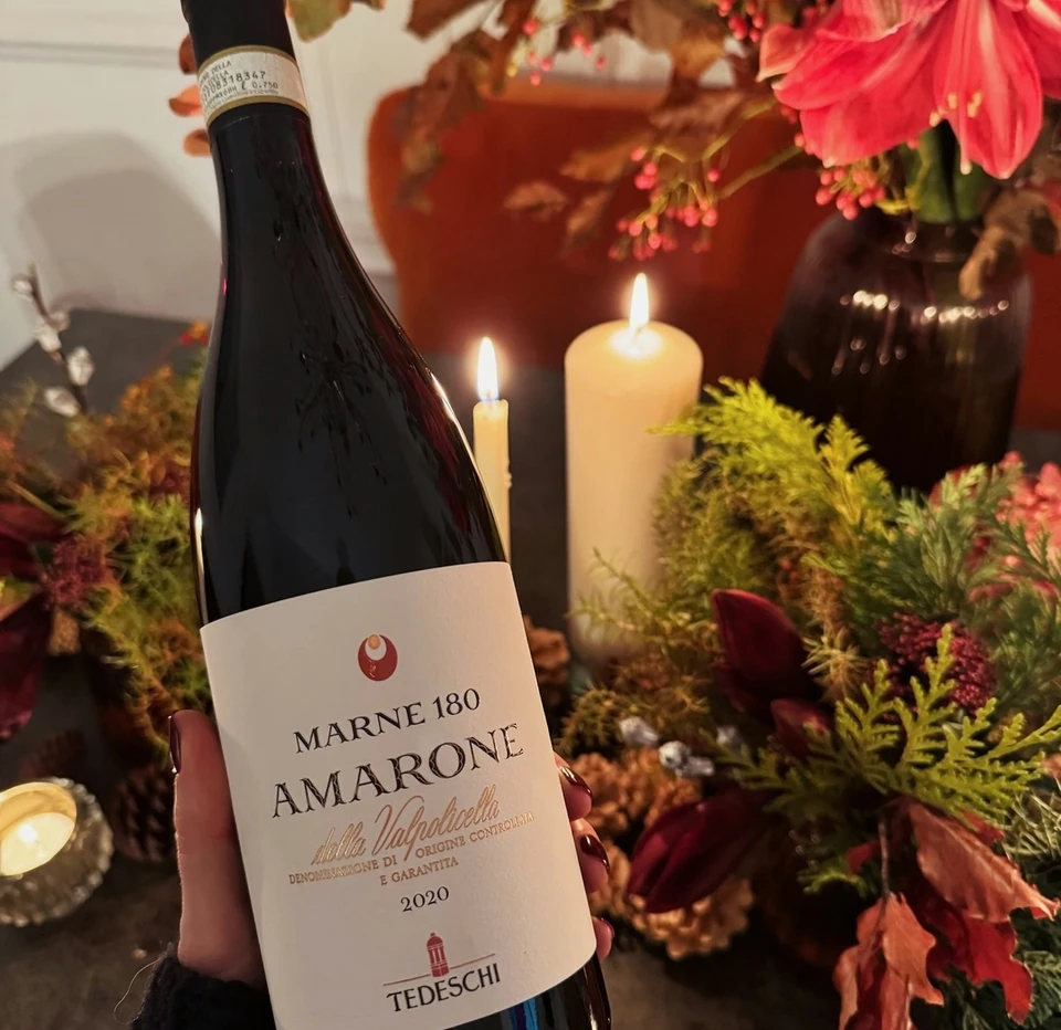 Tedeschi Marne 180 Amarone bottle held beside flowers and lit candles