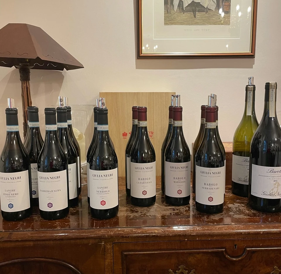 Giulia Negri Barolo and Langhe wine bottles displayed on a wooden sideboard
