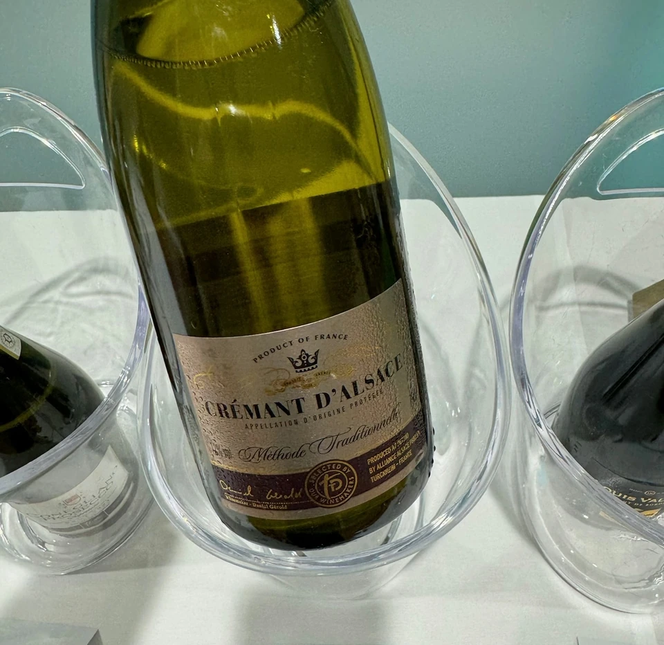 Bottle of Crémant d’Alsace Brut displayed in a glass ice bucket with tasting glasses