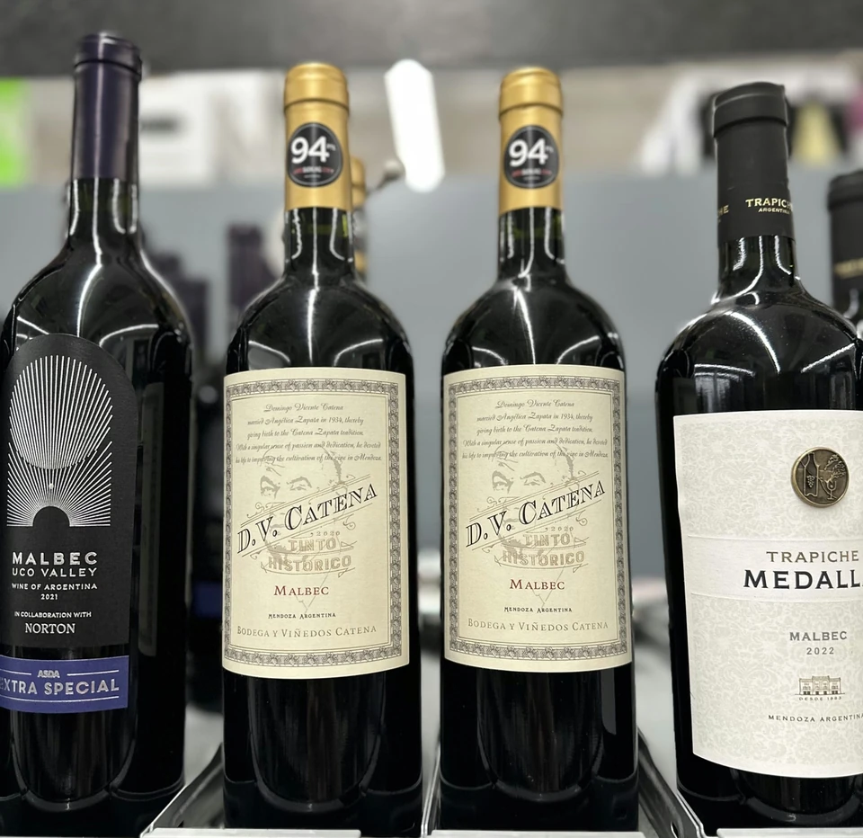 Malbec bottles displayed on a supermarket shelf, including D.V. Catena and Trapiche Medalla wines