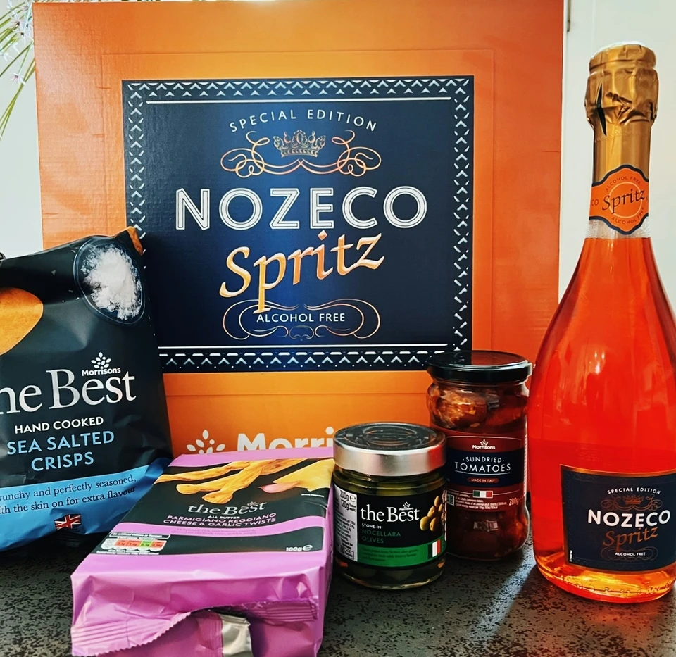 Nozeco Spritz with Morrisons The Best crisps, olives and sundried tomatoes on a kitchen worktop