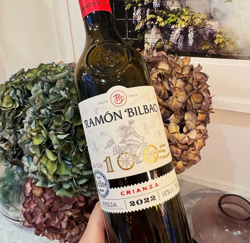 Ramon Bilbao Crianza Rioja 2022 wine bottle held in front of dried flowers