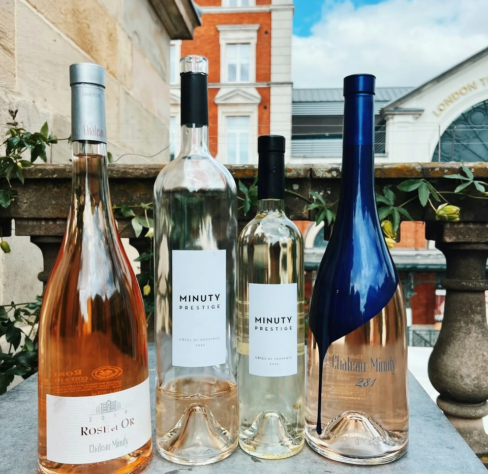 Four Château Minuty rosé wine bottles displayed on a rooftop terrace overlooking London architecture