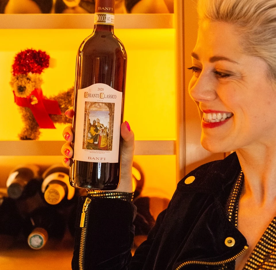 Elizabeth holding a Banfi Chianti Classico bottle in front of a wine display