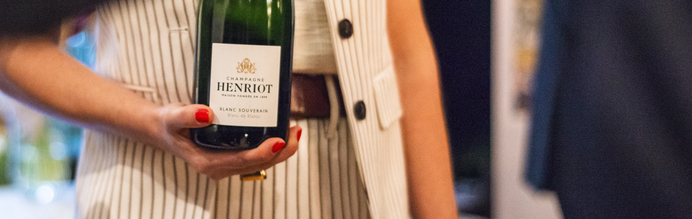 A bottle of champagne passed between two people at an event