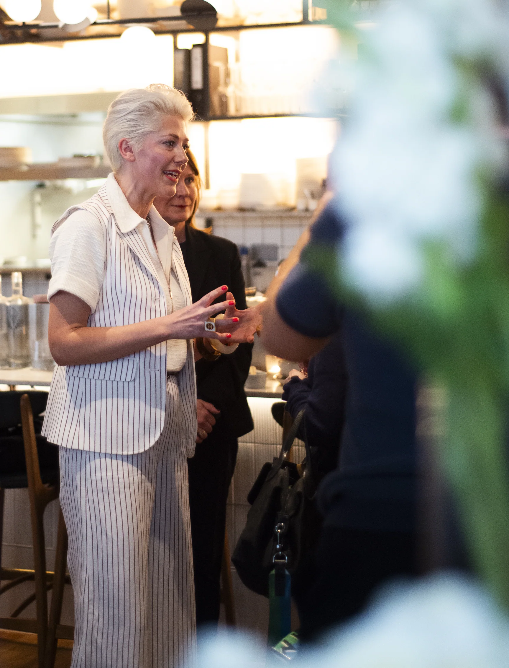 Elizabeth Hawthornthwaite talking with a guest at an event, framed by white blossom
